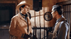Two men dressed in Western attire stand indoors, facing each other with serious expressions—one sporting a cowboy hat and gloves, the other a vest—which creates an authentic old West setting with rustic walls and bars, reminiscent of a classic movie scene. This striking image evokes the tense atmosphere found in “Kill Johnny Ringo (1966)” and is perfect for collectors of Spaghetti Western treasures on DVD.