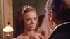 A woman with long brown hair and a white headband looks intently at a man in a suit, who is facing her. The background, featuring a lamp and patterned wallpaper, evokes the timeless atmosphere found in rare classic films such as Kill Johnny Ringo (1966), now available on DVD.