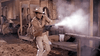 A cowboy in tan clothing fires a revolver, creating a smoke burst amid a gunfight in front of an old wooden building in a Western town—capturing the intense atmosphere found in rare classics like *Kill Johnny Ringo (1966)*, now available on DVD.