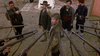 Two men stand surrounded by soldiers aiming rifles at them. The scene is tense, outdoors, with rugs and tents visible in the background. The men look defiant while soldiers point their weapons from all sides—a powerful moment captured in Dust (2001) DVD, a must-have for collectors of rare movies on DVD seeking gripping and atmospheric cinema.
