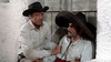 A man in a black hat kneels beside another injured man wearing a large sombrero and white shirt, leaning against a wooden door—a scene that evokes the rustic, old-fashioned atmosphere of 1960s western cinema found in rare movies like Five for Revenge (1966) on DVD.