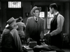 Three men in Western attire talk around a table in a dim, old-fashioned room; one stands behind the table, one sits, and another stands wearing a suit and cowboy hat—capturing the timeless atmosphere of classic western films like “Trail Street (1947)” now available on DVD.