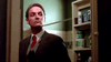 A man in a suit and tie stands in a bathroom beside an open cabinet filled with toiletries, his serious expression evoking the tense mood of The Stepfather (1987) DVD.