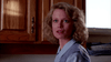 A woman with wavy blonde hair, dressed in a blue collared shirt and lavender sweater vest, stands in a kitchen like a memorable moment from The Stepfather (1987) DVD.