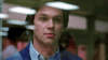 A man with short brown hair looks out through a glass window, his expression neutral. Blurred reflections and lights shimmer on the glass in front of him, evoking scenes from “Stalking Laura (1993) DVD,” a rare classic movie.