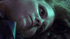 A close-up of a woman’s face illuminated by greenish light as she lies on the ground, eyes open and expression serious, with her head turned slightly to the side—evoking the eerie cult-horror atmosphere captured in Clownado (2019), available on DVD.