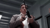 A man in a suit stands indoors, loading a magazine into a rifle equipped with a silencer, exuding the focused intensity of someone straight out of an ’80s sci-fi action thriller—much like the unforgettable scenes found in *The Hidden (1987)* DVD, prized by movie collectors.