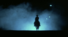 A silhouette of a person on horseback is seen against a blue, smoky background at night, illuminated by distant streetlights—evoking the haunting atmosphere captured in the “Near Dark (1987) DVD.”.