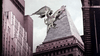 A massive, winged dragon looms atop the spire of a towering city skyscraper beneath a cloudy sky, capturing the thrilling imagery of *The Winged Serpent (1982)*—a cult monster film cherished by DVD collectors and fans of rare movies.