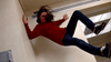 A person in a red sweater and jeans appears to be falling sideways in a hallway, their hair flying and limbs outstretched, evoking a sense of motion and surprise—reminiscent of the suspenseful moments captured with striking intensity in “The Sender (1982)” DVD.