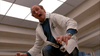 A man in a white lab coat leans forward with a startled, wide-eyed expression in a bright, modern room with ceiling lights, as if he’s just witnessed one of the most chilling moments from “The Sender (1982)” on DVD.