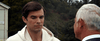A young man in a white hoodie gazes down thoughtfully as an older, gray-haired man talks to him outside, surrounded by trees and buildings—evoking the kind of heartfelt scene you’d find in a film like “A California Christmas: City Lights (2021)” on DVD.