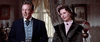 A man in a dark suit with a blue vest and a woman in Victorian attire stand indoors, evoking Western suspense, as light streams through curtains behind them. Featured on the "Ride A Crooked Trail (1958) DVD.