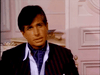 A man with dark hair in a black pinstripe suit and blue cravat sits indoors against an ornate wall, his serious expression capturing the intrigue of rare finds like the Monte Carlo (1986) DVD or classic TV miniseries.