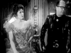 A woman in an ornate gown poses beside a man in glasses and a leather jacket in a classic black-and-white setting—evoking scenes from "The Slowest Gun in the West (1960)" DVD.