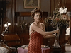 A woman in a red sequined dress holds a large vase of flowers, appearing startled, in an elegantly decorated room with wood paneling and a round table behind her—a scene reminiscent of those found in The Counterfeit Contessa (1994) DVD.