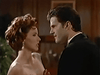 A woman with red hair in a strapless dress stands close to a man in a suit indoors, their serious gazes locked—a moment echoing the classic romantic tension found on The Counterfeit Contessa (1994) DVD, evoking the timeless allure of unforgettable onscreen pairs.