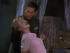A man in uniform restrains a distressed woman in a pink shirt, leaning backward, amid plastic-covered items in a dimly lit room—evoking an intense scene from the "Breach of Conduct (1994) DVD.