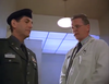 A man in a military uniform stands next to a man in a white lab coat, both indoors under bright lighting, appearing to have a serious conversation—evoking the intense atmosphere of classic films like "Breach of Conduct (1994)" on DVD.
