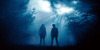 Two people stand side by side in a dark, misty forest, illuminated by shafts of light piercing through the trees, evoking a mysterious and dramatic mood reminiscent of "Bloodsuckers and the Grimoire (2024)"—the cult favorite horror-comedy about vampire hunters, now available on DVD.