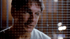 A man with short brown hair is seen behind a grid or mesh, lit from the side, with a serious expression on his face—evoking the intensity of the "And Never Let Her Go (2001) DVD" true crime miniseries. The background is dark and slightly blurred.