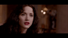 A woman with wavy dark hair and red lipstick looks slightly concerned, with blurry lights and a figure in the background—evoking the suspenseful style of scenes from The Frighteners (1996) DVD.