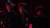 Three kids stand in a dimly lit room bathed in colorful light; the one in the middle clutches a prized copy of Little Monsters (1989) DVD. Dressed in casual, quirky outfits—a backward cap and glasses among them—they gaze ahead with serious focus, as if poised to embark on an adventure straight out of this cult favorite classic.