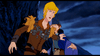 Two animated characters stand close together against a dark, stormy background. One has blond hair and a decorated brown outfit, while the other wears blue robes and a pointed hat, reaching out with concern—evoking the magical charm of an animated fantasy film or beloved rare classics like The Last Unicorn (1982) DVD.