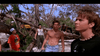 A group of young people stand outdoors among fallen trees in a scene reminiscent of a martial arts film, evoking the intensity and drama found in “Only the Strong (1993) DVD.” One is shirtless, while another wears a black shirt with a beaded necklace, adding to the tense and dramatic atmosphere.