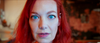 A person with bright red hair and striking blue eyes stares directly into the camera, their face filling most of the frame against a blurred background—an image reminiscent of characters featured in the rare film “Bad Fish (2024)” on DVD.