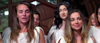 A group of women in white robes stand together indoors, some with serious expressions and others sharing soft smiles, as if united by a secret from “Bad Fish (2024)” on DVD. Natural light streams in through the windows behind them.
