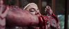 A woman with a pearl headband bites into a bloody severed foot, gripping it with both hands—an unforgettable moment from Bad Fish (2024) DVD that earns its place in any extreme survival thriller collection.