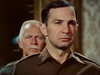 Two men in military uniforms—a stern-faced figure in the foreground and another standing behind—capture the gripping suspense of “Fireball Forward” (1972) on DVD. The patterned wall in the background adds to the classic World War II ambiance evoked by this film.