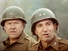 Two men in military uniforms and helmets—one distinguished by two stars and a cigar—stand outdoors amid blurred greenery, their gaze fixed in the same direction, evoking a suspenseful scene from *Fireball Forward* (1972), now available on DVD.