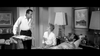 A man stands by a hospital bed with a tray, talking to a woman seated beside the bed and a bearded man lying down. The room is simply decorated with paintings and lamps, evoking the timeless charm often seen in classic films like *The World, The Flesh and the Devil* (1959) on DVD.