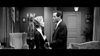 A man and woman stand facing each other in a vintage, elegantly furnished living room, engaged in an intense conversation—evoking the dramatic scenes from classic black-and-white films like “The World, The Flesh and the Devil” (1959) on DVD.