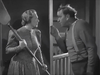 A tense black and white indoor scene from the classic Western film “20 Mule Team (1940)” DVD captures a dramatic moment as a woman wields a large paddle while confronting a man in suspenders.