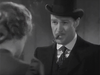 A man in a suit and bowler hat smokes a cigar, facing a woman with her back to the camera, in this black-and-white image that evokes the vintage style of classic films like *20 Mule Team (1940)*.