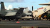 Navy fighter jets and an aircraft sit on the deck of an aircraft carrier as crew members work nearby beneath a partly cloudy sky—a scene reminiscent of what’s depicted in *Tiger Cruise (2004) DVD*, which captures the spirit of service and adventure.