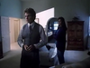 A man in a vest stands in a dimly lit living room, looking serious, while a woman lingers behind him near a sofa. Light spills through an arched doorway into another room, creating the suspenseful atmosphere reminiscent of amnesia films often featured among rare classic movies or on sought-after DVD releases like Lightning In A Bottle (1993).