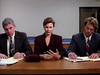 Three people in business attire sit at a table with papers, appearing serious and focused. The woman in the center looks at her hands while the men on either side write or review documents, evoking a tense boardroom scene reminiscent of an amnesia movie or one of those rare classic films you might find on a Lightning In A Bottle DVD (1993).