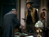 A man in a cowboy outfit holds a gun while another man in a suit opens a bag at a desk, with a third man in the background wearing a hat—a gripping moment from the film classic “Gun Belt (1953)” on DVD, ideal for fans of cowboy cinema and vintage western adventures.