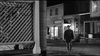 A man in a hat walks alone down a dimly lit street in an old western town at night, echoing the suspense of classic Westerns. Wooden buildings and a slatted fence set the scene from Man With The Gun (1955) DVD.