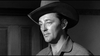 A man in a cowboy hat stands before a wooden door in this black-and-white scene from Man With The Gun (1955) DVD, capturing the classic Western movie spirit.
