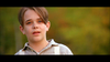 A young boy with parted brown hair and blue eyes, dressed in a light shirt and suspenders, stands outdoors with a blurred green backdrop—evoking the classic film Tall Tale (1995) DVD.