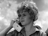 A young woman with a short hairstyle holds a portable telephone to her ear while looking thoughtfully to the side, evoking the style of the Kiss Her Goodbye (1959) DVD.