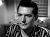 A black-and-white close-up of a man in a striped shirt looking thoughtfully off-camera, as if reflecting on the Kiss Her Goodbye (1959) DVD.