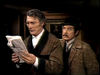 In a scene from The Strange Case of Dr. Jekyll and Mr. Hyde (1968) DVD, a man in a dressing gown reads a newspaper while Jack Palance, wearing a bowler hat and coat, looks over his shoulder.