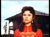 A woman with dark hair in a red high-collared garment looks toward the side in front of a house, as seen on the cover of The White Warrior (1959) DVD.