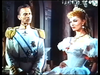 A man in a military uniform with gold epaulets stands looking at a woman in an elaborate white gown and tiara in this scene from The White Warrior (1959) DVD, featuring Steve Reeves.